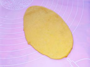 取一个面团压扁，用擀面杖擀成长舌形，