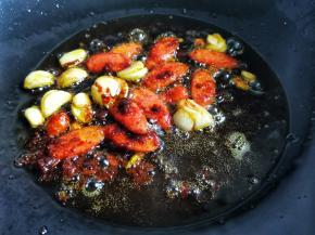 另起锅热油，加入大蒜火腿、炒香，加1勺豆瓣酱炒出红油，