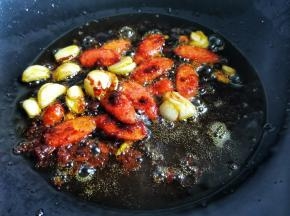另起锅热油，加入大蒜火腿、炒香，加1勺豆瓣酱炒出红油，