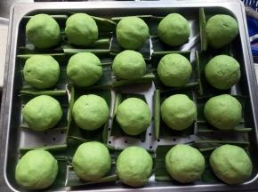 逐个包好，搓圆，摆上垫了山姜叶的蒸盘