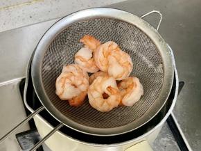 把虾仁下沸水煮至卷曲变红；