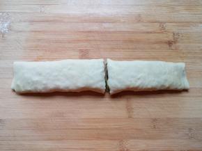 卷起来，用手压一下，从中间切开，一个生的韭菜卷就做好了，依次做完剩下的面团。 