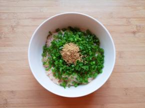 将剁好的肉馅放入大碗里，放上葱花和十三香。 