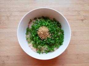 将剁好的肉馅放入大碗里，放上葱花和十三香。 