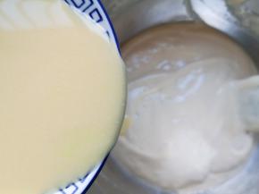 顺着盆边加入混合好的牛奶和玉米油，翻拌均匀。 