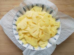 盘子里铺上厨房用纸，放上菠萝片吸一下多余的水分。 