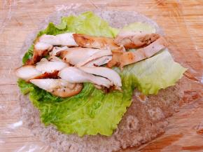 底下铺上保鲜膜，摆上黑麦卷饼再放一片生菜，摆上鸡腿肉卷起来，借助保鲜膜能卷的很紧吃起来也干净方便