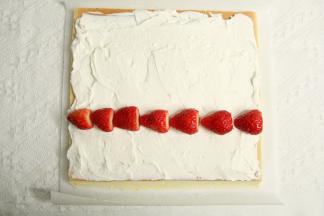 毛巾面朝下，奶油均匀抹在卷上，尾部留一点不抹，1/3处排上草莓，剩余一点淡奶油可将空隙填满。