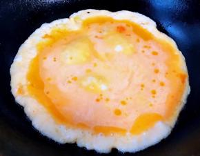 锅中倒入适量底油加热后淋入打散的蛋液炒至鸡蛋八成熟