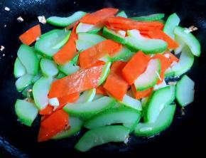 另起锅倒入底油加热放入蒜粒爆香再放入西葫芦和胡萝卜大火快速翻炒均匀