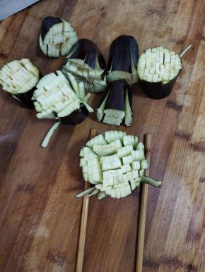 底下垫两根筷子，按照图片上的方法把茄子切成小细条，注意不要切断了！