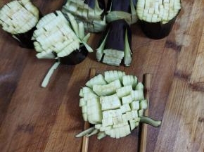 底下垫两根筷子，按照图片上的方法把茄子切成小细条，注意不要切断了！