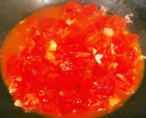 锅中倒入底油加热放入蒜粒爆香再放入西红柿大火快速翻炒出汤汁