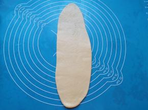 取一份面包面团擀开成牛舌状。 