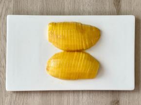 把芒果的皮用削皮刀削掉，先对半切开，再切成片。