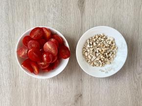 圣女果对半切好，腰果放入保鲜袋，用擀面杖碾碎备用。