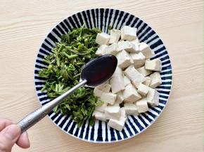 把香椿碎和豆腐块放入盘中，加入一勺生抽；