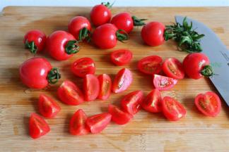 圣女果去蒂，对半切，或者切四块。挑选圣女果要选择椭圆形的，越熟的圣女果，越甜。其实挑选番茄也是一样的道理，越熟越甜，营养价值也越高。