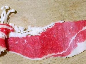 冷冻的肥牛片微微解冻后取一片展平取适量金针菇放在肥牛片一侧顺一个方向紧紧的卷起