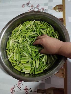 切好的蒜苔放入盆中，向里面加入没过蒜苔的清水。再加入两勺盐，抓一抓使盐化开！（这样可以去除蒜苔的辛辣味，吃的时候不烧心！）