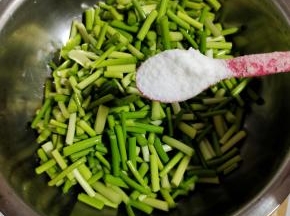 浸泡好的蒜苔，捞出沥干水分，放入盆中，加入两勺盐翻拌均匀！