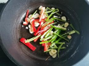 煮面同时，锅中加入普通食用油烧热，倒入蒜片，将蒜片煎炒到微黄，加入青红椒丝，翻炒1分钟，