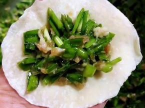 取适量馅料放在饺子皮中间饺子皮对折捏紧两端空着不要捏住