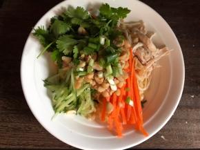 沥干水分装入大碗中，码入黄瓜丝、胡萝卜丝、香菜和鸡丝，加入花生碎和葱花