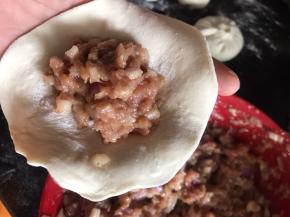 用擀面杖擀成厚面皮，放入洋葱肉馅