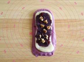 取一擀开成长方形，翻面后放上扯开成差不多形状的麻薯，放上紫薯泥，熟核桃碎和蔓越莓。