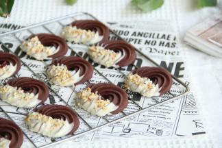 冷凉好的曲奇，一边蘸上适量白巧克力，撒上榛子仁碎，喜欢果干或者蔓越莓的小伙伴，可以加一些蔓越莓碎。