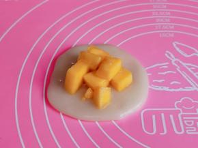 取一块小糯米团压扁。放上芒果肉包起来，裹上椰蓉即可。