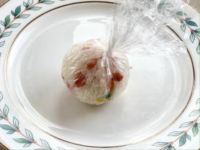 借助保鲜膜把米饭裹紧，揉圆；