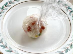 借助保鲜膜把米饭裹紧，揉圆；