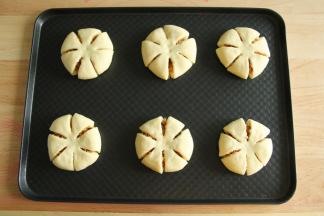 还是用把边缘往中心折叠的方法，收口捏紧朝下，按扁后均匀切成6等份，中心点无需切断。整形好排入烤盘。