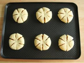 还是用把边缘往中心折叠的方法，收口捏紧朝下，按扁后均匀切成6等份，中心点无需切断。整形好排入烤盘。