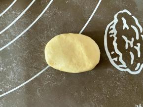 取一个小剂子揉成圆形，稍微搓长，轻轻按扁成椭圆形。面团如果比较粘手，可以在手上抹点油后再整形。