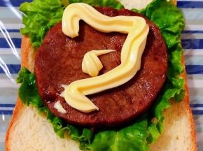 保鲜膜平铺在底部摆上一片吐司放上生菜再摆上牛排淋上沙拉酱