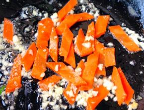 另起锅倒入底油加热放入蒜粒爆香再放入胡萝卜片炒匀