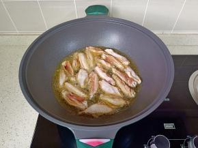 锅里放宽油，油温五成热放入鸡翅煎。