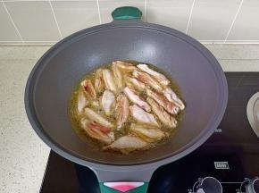 锅里放宽油，油温五成热放入鸡翅煎。