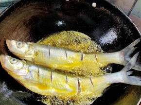 放入腌制好的白鱼。调中小火慢慢的煎，中途把锅晃动一下！