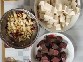 嫩豆腐和鸭血清洗一下，切成小块，蒜瓣剁成蒜末，生姜切成小丁，干辣椒切成段备用！