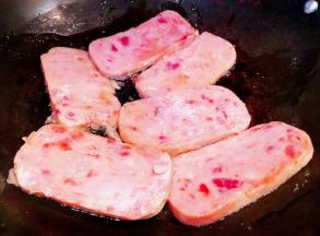 午餐肉切成厚薄均匀的大片锅中倒入油加热午餐肉放入锅中中小火慢煎 一面煎至熟透轻轻翻过来煎至另一面熟透即可