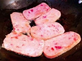 午餐肉切成厚薄均匀的大片锅中倒入油加热午餐肉放入锅中中小火慢煎 一面煎至熟透轻轻翻过来煎至另一面熟透即可