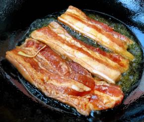 锅中倒入底油加热放入入味的五花肉中火煎起来