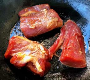 锅中倒入底油加热放入入味的里脊肉中火煎制
