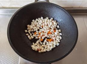 锅里留底油，倒入杏鲍菇丁和胡萝卜丁翻炒。