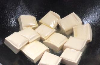 加入豆腐，中火煎香，煎至两面金黄