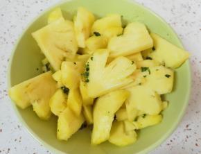 用淡盐水浸泡过的菠萝片切成小块，和薄荷叶放在一起搅拌均匀。